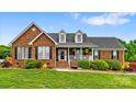 Charming brick home with manicured lawn, dormers, and inviting front porch with decorative shrubbery at 6713 Edwards Farm Ln, Monroe, NC 28110