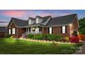 Charming brick home with manicured lawn, dormers, and inviting front porch with decorative shrubbery at 6713 Edwards Farm Ln, Monroe, NC 28110
