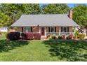 Inviting single-story house with well-kept lawn, cozy front porch, and red front door at 806 Mcgregor Ne Dr, Concord, NC 28025