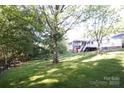 A big backyard with lush greenery, a deck, a screened in back porch and play equipment at 854 Silver Fox Dr, Concord, NC 28025