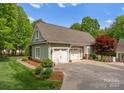 View of a detached garage with white doors, surrounded by lush greenery, and a paved driveway at 174 Buffalo Creek Dr, Statesville, NC 28677