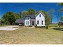 A two-story white farmhouse with a well-manicured front lawn, car port, and plenty of land at 5028 Lewis Rd, Gastonia, NC 28052