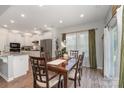 Dining room with natural light, featuring a wooden table with six chairs, connected to the kitchen at 6040 Fazio Ct, Harrisburg, NC 28075