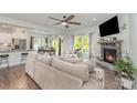 Open-concept living room with a stone fireplace, hardwood floors, and backyard views at 6040 Fazio Ct, Harrisburg, NC 28075