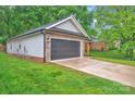 A detached garage boasts a gray door, brick accents, and a well-maintained green lawn at 7328 Starvalley Dr, Charlotte, NC 28210