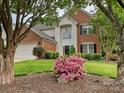 Two-story brick home with manicured front lawn, and landscaped yard featuring flowering shrubs at 13237 Fremington Rd, Huntersville, NC 28078