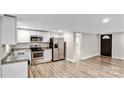 Open kitchen with stainless steel refrigerator, granite countertops, white cabinets, and wood-look flooring at 143 Phifer Cir, Kings Mountain, NC 28086