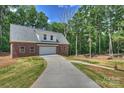 Detached brick garage with a long concrete driveway and surrounded by lush greenery and mature trees at 3009 Brooks Mill Ln, Wingate, NC 28174