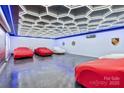 Showroom garage featuring multiple covered luxury vehicles, polished floor, and modern ceiling with geometric lighting at 3009 Brooks Mill Ln, Wingate, NC 28174