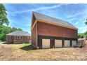 Large detached garage featuring multiple doors with a large grassy area and home in the background at 3009 Brooks Mill Ln, Wingate, NC 28174