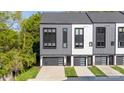 Modern townhome featuring gray and white siding, black trim, and a private garage and driveway at 3538 Saker Ln, Charlotte, NC 28211