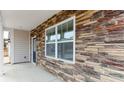 Close-up showcases a stone facade, large windows, and a covered porch with stone accents and a blue front door at 4615 Harris Elliot Rd, Lincolnton, NC 28092