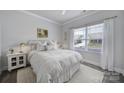 Bright bedroom with a large window, white bedding, and minimalist decor creating a cozy retreat at 5101 Helmsworth Dr, Waxhaw, NC 28173