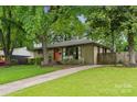 Well-maintained ranch-style home with an orange front door, landscaped yard, and a long driveway at 513 Inwood Dr, Charlotte, NC 28209