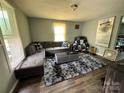 Spacious living room featuring a large gray sectional sofa, dark floors, and bright natural light at 739 Old Charlotte Sw Rd, Concord, NC 28027