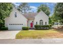 Inviting home with a two-car garage, green lawn, tidy bushes, and striking red front door at 9066 Tulagi Ct, Tega Cay, SC 29708