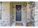 Close-up of the front door, complete with a decorative wreath, flowers and welcome mat at 1004 Princesa Dr, Matthews, NC 28104
