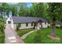 Aerial view of a charming single-story home with a lush lawn, mature trees, and a brick walkway leading to the entrance at 1118 Crestbrook Dr, Charlotte, NC 28211