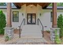 Inviting front entrance with black double doors, wooden pillars, painted brick, and stone accents create a modern aesthetic at 1118 Crestbrook Dr, Charlotte, NC 28211