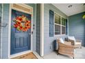 Inviting front porch with a wreath on the front door, wicker furniture, and blue shutters at 1150 Hearth Sw Ln, Concord, NC 28025