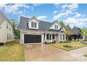 Charming two-story home featuring a stone facade, black shutters, well-manicured lawn, and attached garage at 14119 Shelburne Village Dr, Charlotte, NC 28278