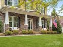 Inviting front porch with stone columns and white benches overlooking a well-manicured lawn at 1515 Millbridge Pkwy, Waxhaw, NC 28173