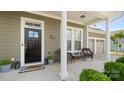 Inviting front porch featuring classic columns, seating area and a black front door at 1963 Felts Pkwy, Fort Mill, SC 29715