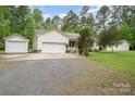Exterior view of a home with multiple detached garages and ample parking space at 204 Millwheel Ln, Mount Gilead, NC 27306