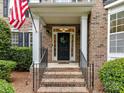 Inviting brick porch with black door, American flag, and well-maintained landscaping at 3203 Blackburn Dr, Waxhaw, NC 28173