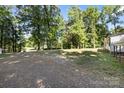 Expansive backyard with gravel, offering ample space and privacy amidst mature trees at 3317 Treyburn Dr, Midland, NC 28107