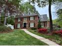 Charming brick home with well-manicured lawn, colorful azaleas, and paved walkway at 3804 Bellingham Ln, Charlotte, NC 28215