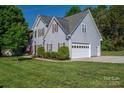 Exterior view of the home featuring a two-car garage, manicured bushes and lush green lawn at 7905 Sedgebrook E Dr, Stanley, NC 28164