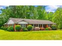 Charming single-story brick home featuring a lush green lawn and colorful landscaping at 1044 Oakridge Farm Hwy, Mooresville, NC 28115