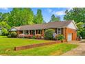 Charming single-story brick home with an attached garage, lush green lawn and colorful landscaping at 1044 Oakridge Farm Hwy, Mooresville, NC 28115