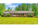 Charming single-story brick home featuring a lush green lawn and colorful landscaping at 1044 Oakridge Farm Hwy, Mooresville, NC 28115