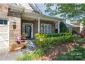 Inviting front porch with a brick entryway, trimmed landscaping, and decorative plants in a charming setting at 11008 Round Rock Rd, Charlotte, NC 28277