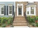 A front entrance with brick steps and black railings, leading to a door with sidelights, complemented by flowering bushes at 11232 Tradition View Dr, Charlotte, NC 28269