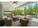 Relaxing covered porch with wicker furniture, a ceiling fan, and a view of the backyard and swimming pool at 1149 Grand Oak Dr, Waxhaw, NC 28173