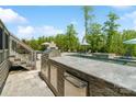Outdoor kitchen with a stone countertop, built-in grill, and stainless steel storage, near the swimming pool at 1149 Grand Oak Dr, Waxhaw, NC 28173