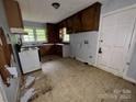 The kitchen features an electric stove, cabinetry, a window, and an exit door with peeling paint at 1224 Bailey St, Albemarle, NC 28001