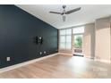 Bright bedroom featuring a dark accent wall, hardwood floors, and a door to a private balcony at 1320 Fillmore Ave # 112, Charlotte, NC 28203