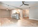 Open-concept living room with light wood floors, bar seating, and a view into the modern kitchen at 1320 Fillmore Ave # 112, Charlotte, NC 28203