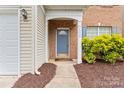 Close-up of front entrance with blue door, brick facade, and green shrubbery at 15009 Medlock Ln, Charlotte, NC 28277