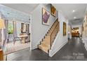 A bright hallway with staircase, elegant artwork, and dark hardwood floors leading to a dining area at 1550 High St, Charlotte, NC 28211