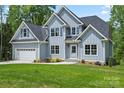 Charming two-story home with a manicured lawn, attached garage, and a combination of vertical and shingle siding at 156 Clear Springs Rd, Mooresville, NC 28115