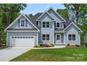 Charming two-story home with a manicured lawn, attached garage, and a combination of vertical and shingle siding at 156 Clear Springs Rd, Mooresville, NC 28115