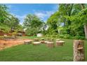 A view of the private backyard featuring mature trees, a sprawling green lawn, and a unique stone fire pit at 1713 Wildwood Dr, Albemarle, NC 28001