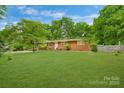 Well-maintained single-story brick home with a lush green lawn and mature trees at 1713 Wildwood Dr, Albemarle, NC 28001