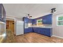 A full view of the vintage kitchen featuring painted blue cabinets, a white refrigerator, and hardwood floors at 1713 Wildwood Dr, Albemarle, NC 28001