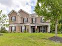 Charming brick two-story home with black shutters, manicured lawn, and American flag displayed by front door at 2369 Baxter Se Pl, Concord, NC 28025